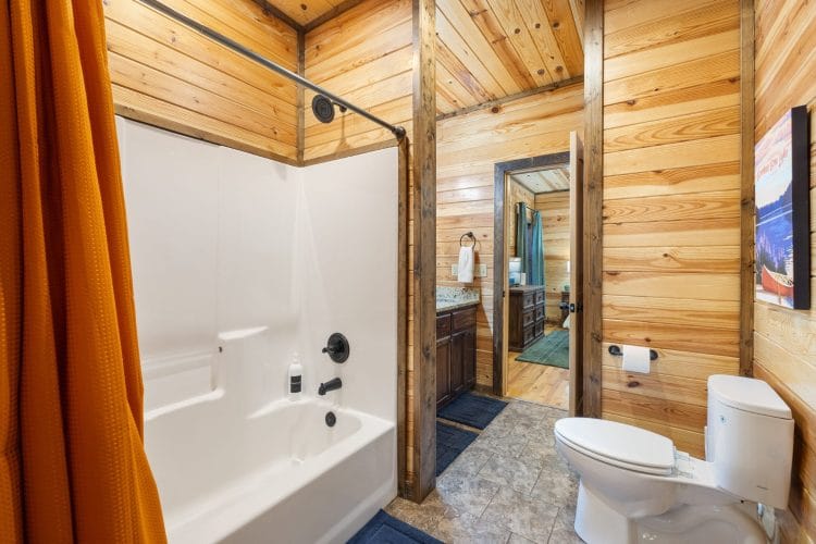 Tub-shower with an orange curtain and a vanity beyond