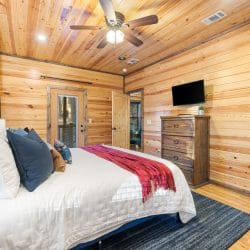 King bed with a blue headboard, a TV and a tall dresser