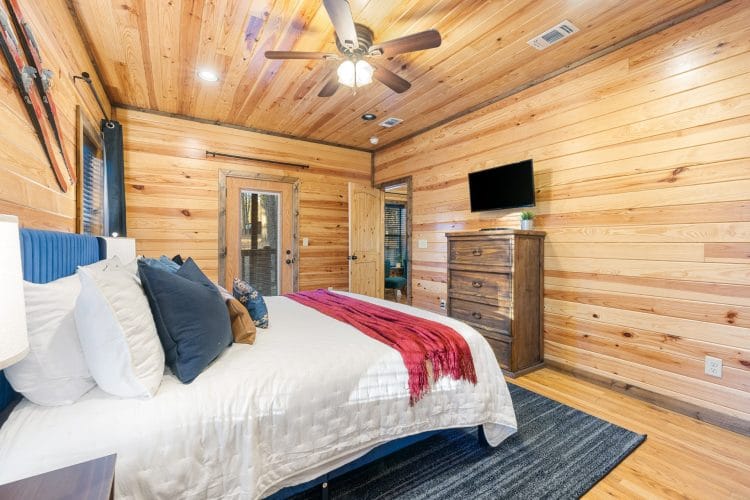 King bed with a blue headboard, a TV and a tall dresser