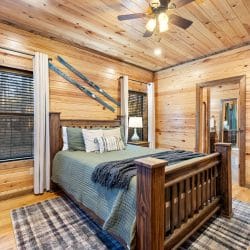 Wood-frame bed with green bedding and skis on the wall