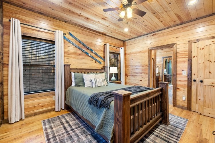 Wood-frame bed with green bedding and skis on the wall