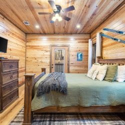 Bed with green bedding, a TV and a dresser