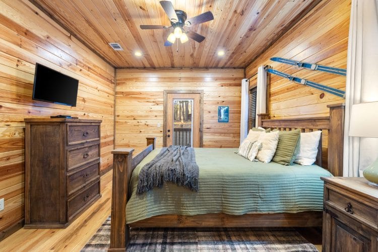 Bed with green bedding, a TV and a dresser