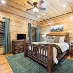 Wood-frame bed with a green rug and teal curtains