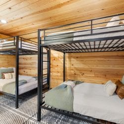 Two metal bunk beds with sage-green bedding
