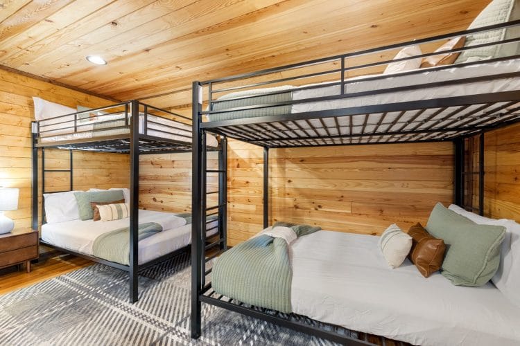 Two metal bunk beds with sage-green bedding