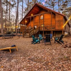 Cabin from the yard with a fire pit, cornhole boards and a picnic table
