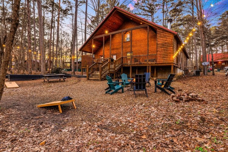 Cabin from the yard with a fire pit, cornhole boards and a picnic table