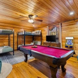 Game room with two metal bunk beds, a pool table, bean bags and an arcade cabinet