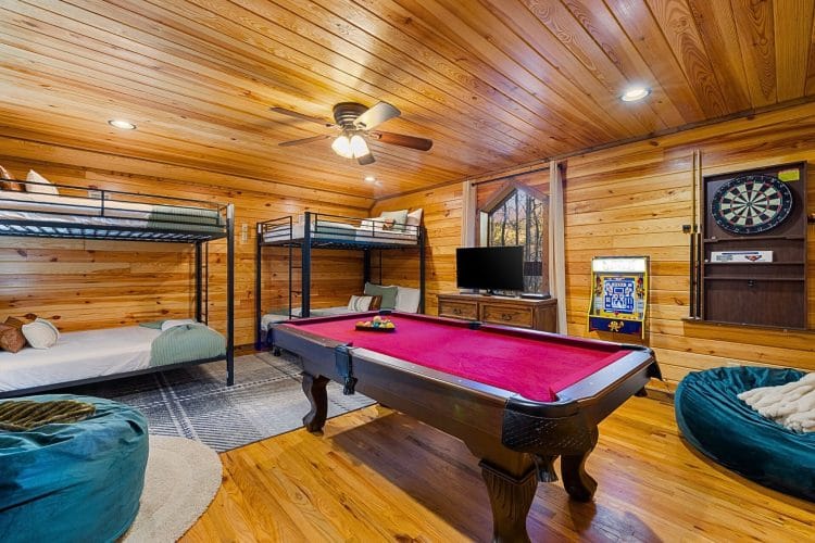 Game room with two metal bunk beds, a pool table, bean bags and an arcade cabinet