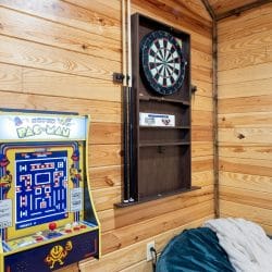 Pac-Man arcade game and a dartboard on the game room wall