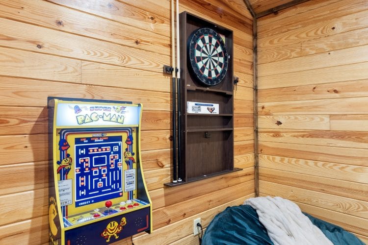 Pac-Man arcade game and a dartboard on the game room wall