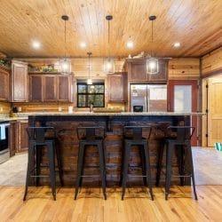 Kitchen with an island bar, four black stools and wood cabinets