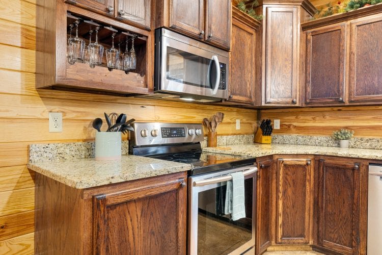 Kitchen range and microwave with a wine glass rack above