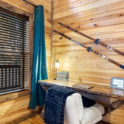 Desk nook by a window with teal curtains and skis on the wall