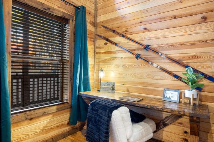 Desk nook by a window with teal curtains and skis on the wall