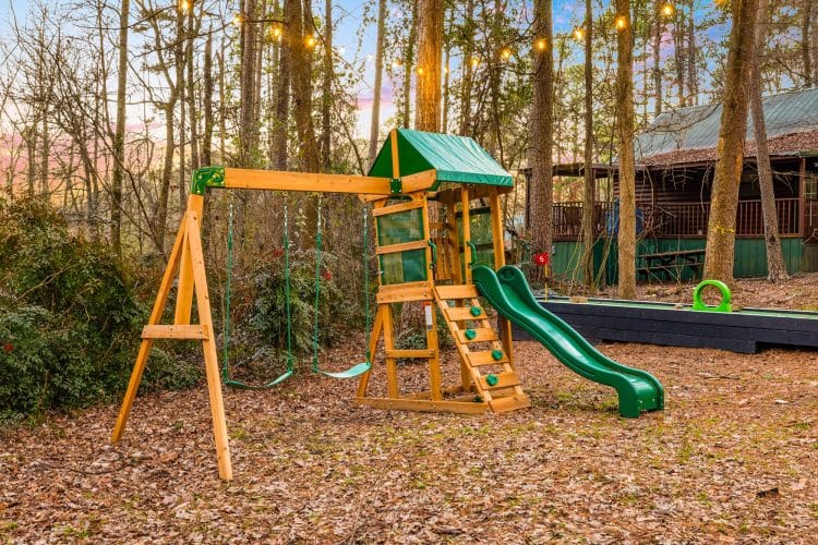 Wooden playset with a green slide in the woods