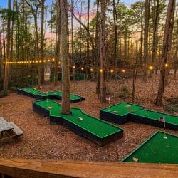 Hand-built mini golf course among the trees under string lights