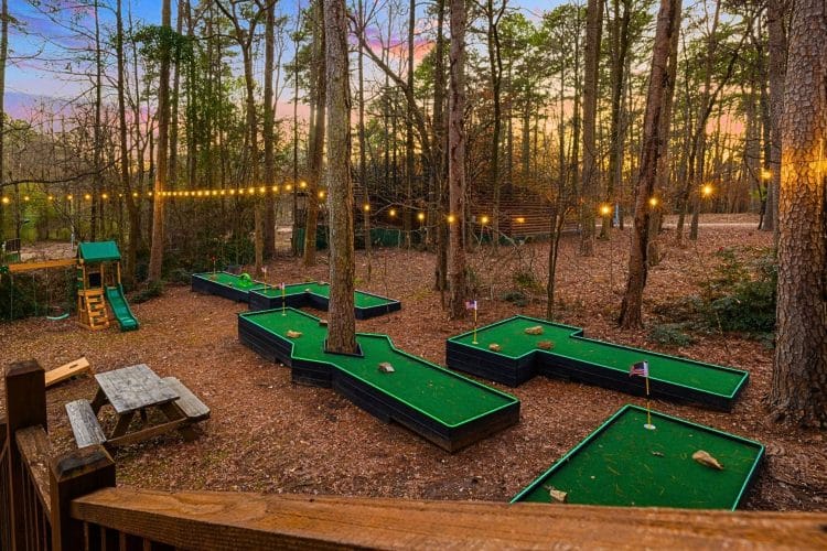 Hand-built mini golf course among the trees under string lights