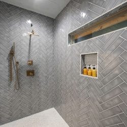 Walk-in shower with gray herringbone tile and a long window niche