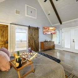 King bed with a breakfast tray and rose petals, a barn door and French doors