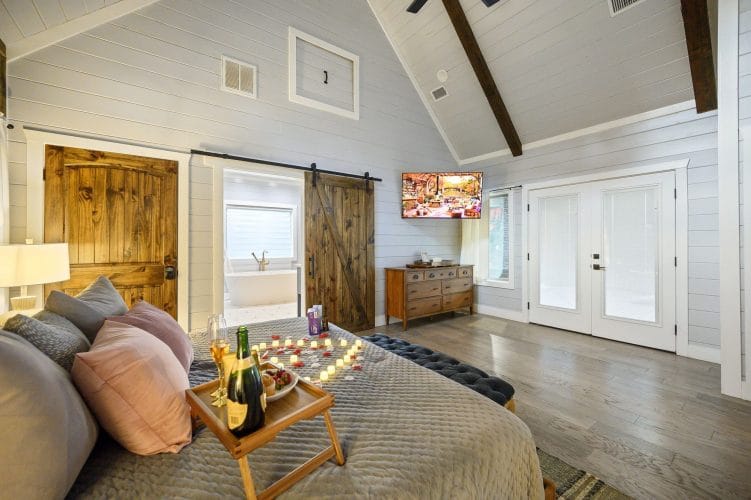 King bed with a breakfast tray and rose petals, a barn door and French doors