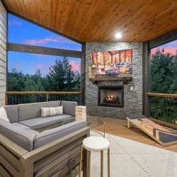 Covered deck with an outdoor sectional, a cornhole board and a gas fireplace