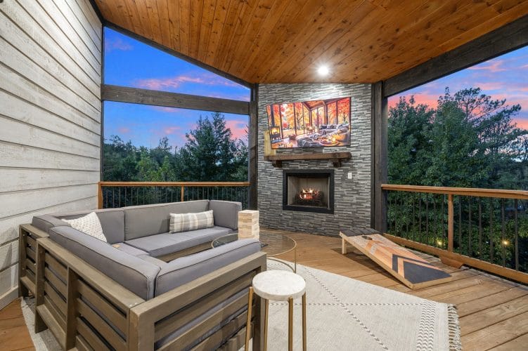 Covered deck with an outdoor sectional, a cornhole board and a gas fireplace