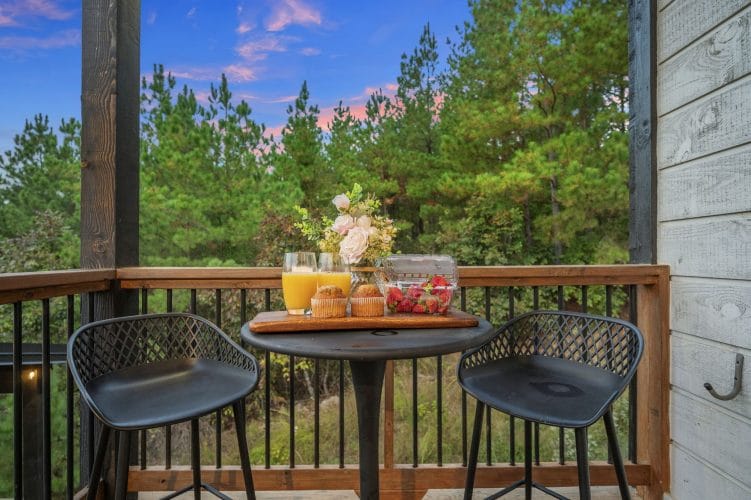 Bistro table and two stools with a breakfast spread, overlooking the trees