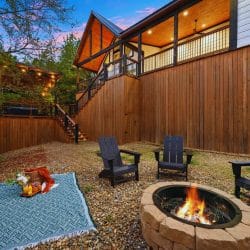 Fire pit with Adirondack chairs and a picnic spread, with the cabin siding behind
