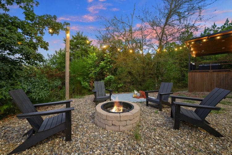 Fire pit with Adirondack chairs and string lights on gravel