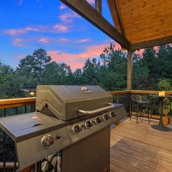 Gas grill on the deck with a bistro table, at sunset