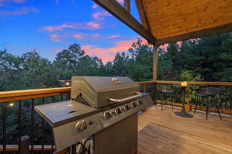Gas grill on the deck with a bistro table, at sunset