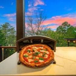Gas-fired pizza oven on a quartz counter with a finished pizza