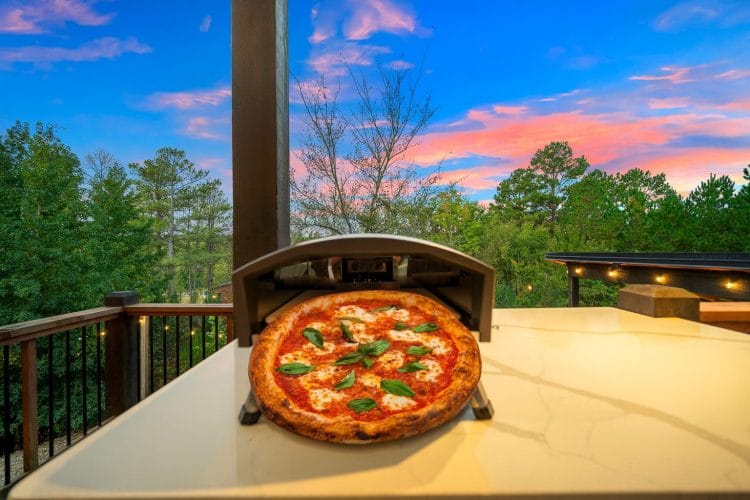 Gas-fired pizza oven on a quartz counter with a finished pizza