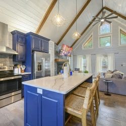 Kitchen with navy cabinets, a white quartz island, a stainless range and wicker bar stools