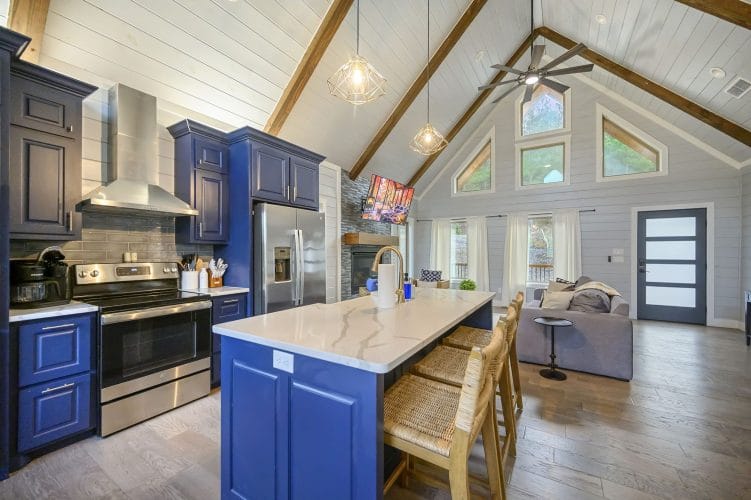 Kitchen with navy cabinets, a white quartz island, a stainless range and wicker bar stools