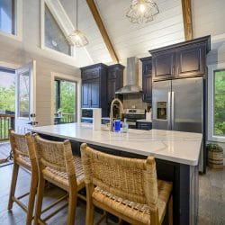 Island with wicker bar stools and an open door to the deck