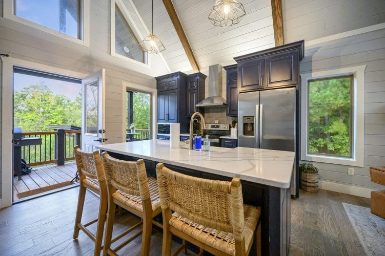 Island with wicker bar stools and an open door to the deck