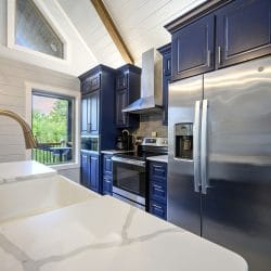 Farmhouse sink in a white quartz counter with a stainless refrigerator behind