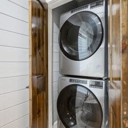 Stacked washer and dryer in a closet behind wood doors