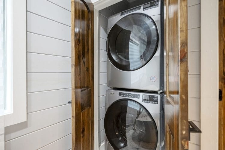 Stacked washer and dryer in a closet behind wood doors