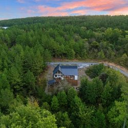Aerial of the cabin in a forested valley at dusk