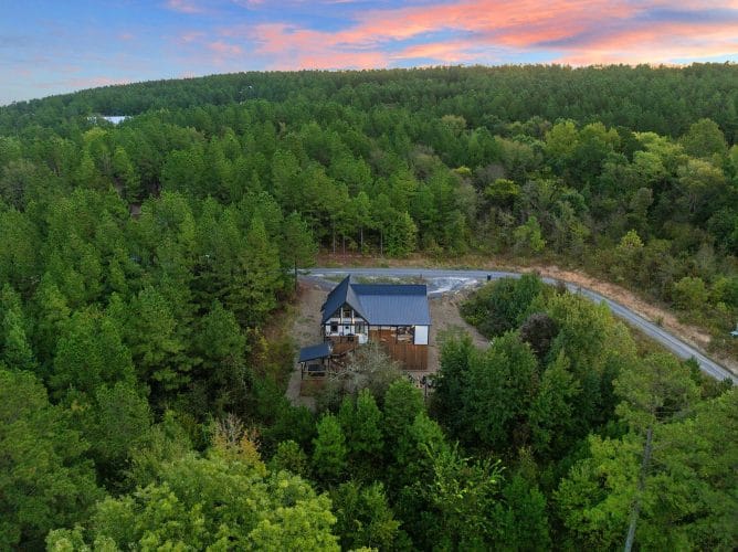 Aerial of the cabin in a forested valley at dusk