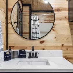 Vanity with a round mirror and a striped shower curtain beside it
