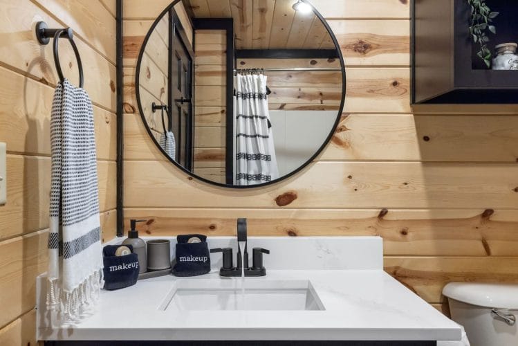 Vanity with a round mirror and a striped shower curtain beside it