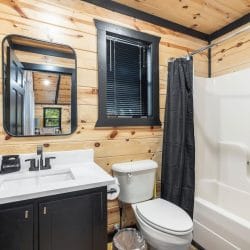 Bathroom with a navy vanity, a tub-shower with a black curtain and a window