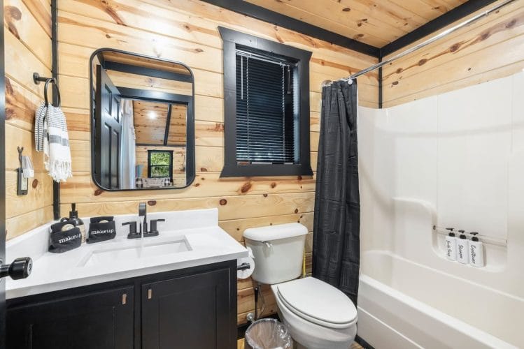 Bathroom with a navy vanity, a tub-shower with a black curtain and a window