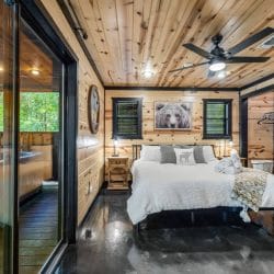 Same bedroom looking toward the sliding glass door and porch, with ceiling fan overhead