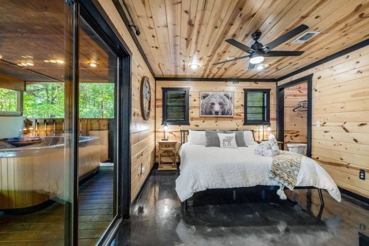Same bedroom looking toward the sliding glass door and porch, with ceiling fan overhead